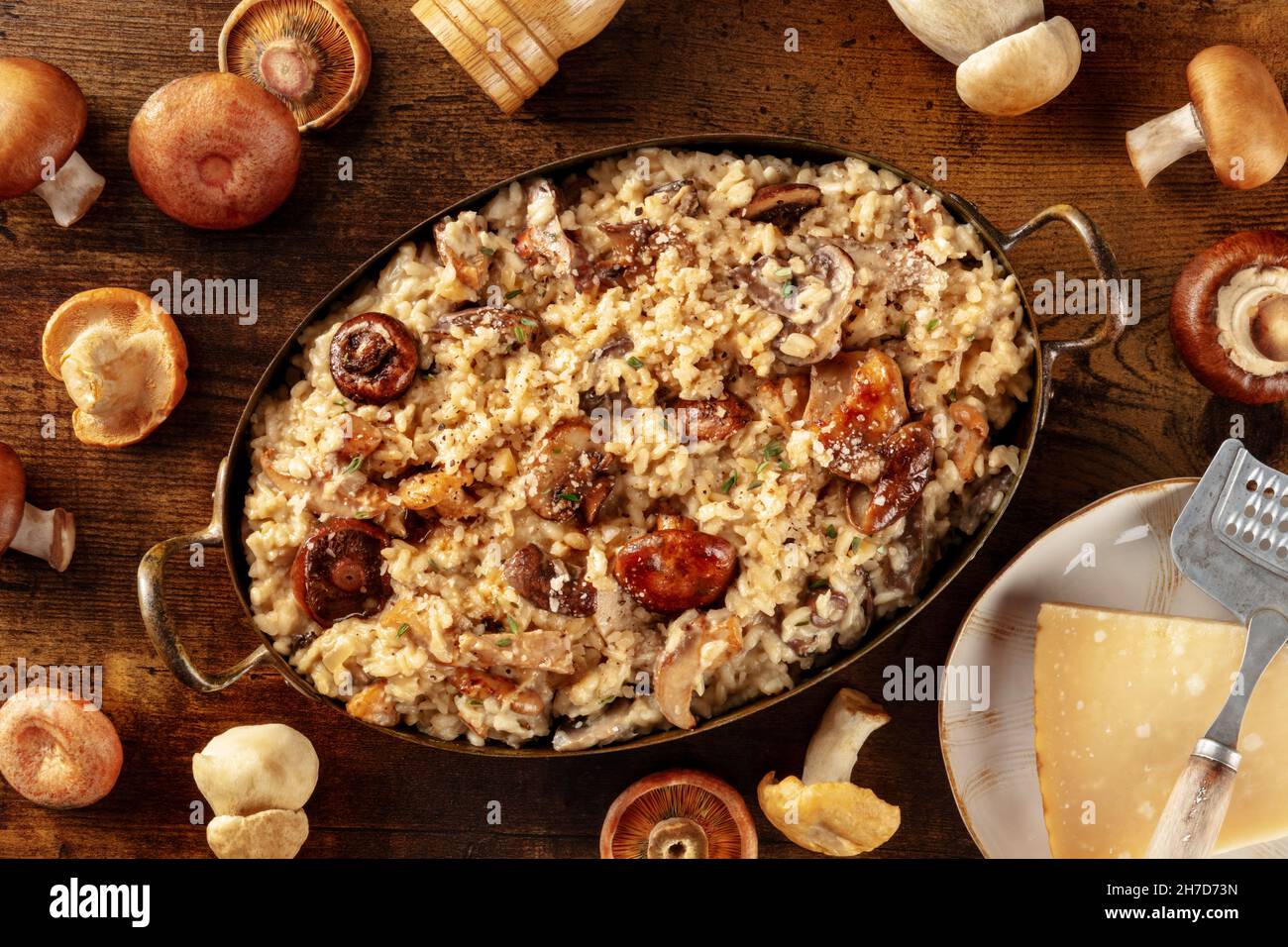 Risotto ai fonghi, risotto aux champignons, riz rustique avec champignons et fromage, grenaille sur fond de bois sombre avec ingrédients Banque D'Images
