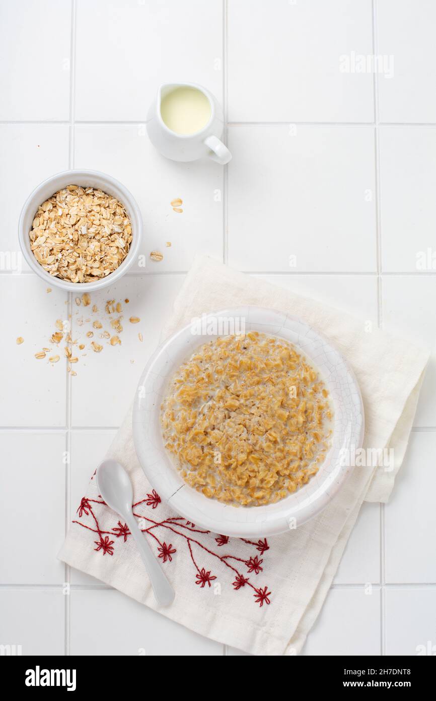 Bouillie de flocons d'avoine simple avec fraises dans une assiette blanche sur une serviette en lin. Petit déjeuner santé concept alimentaire. Vue de dessus Banque D'Images