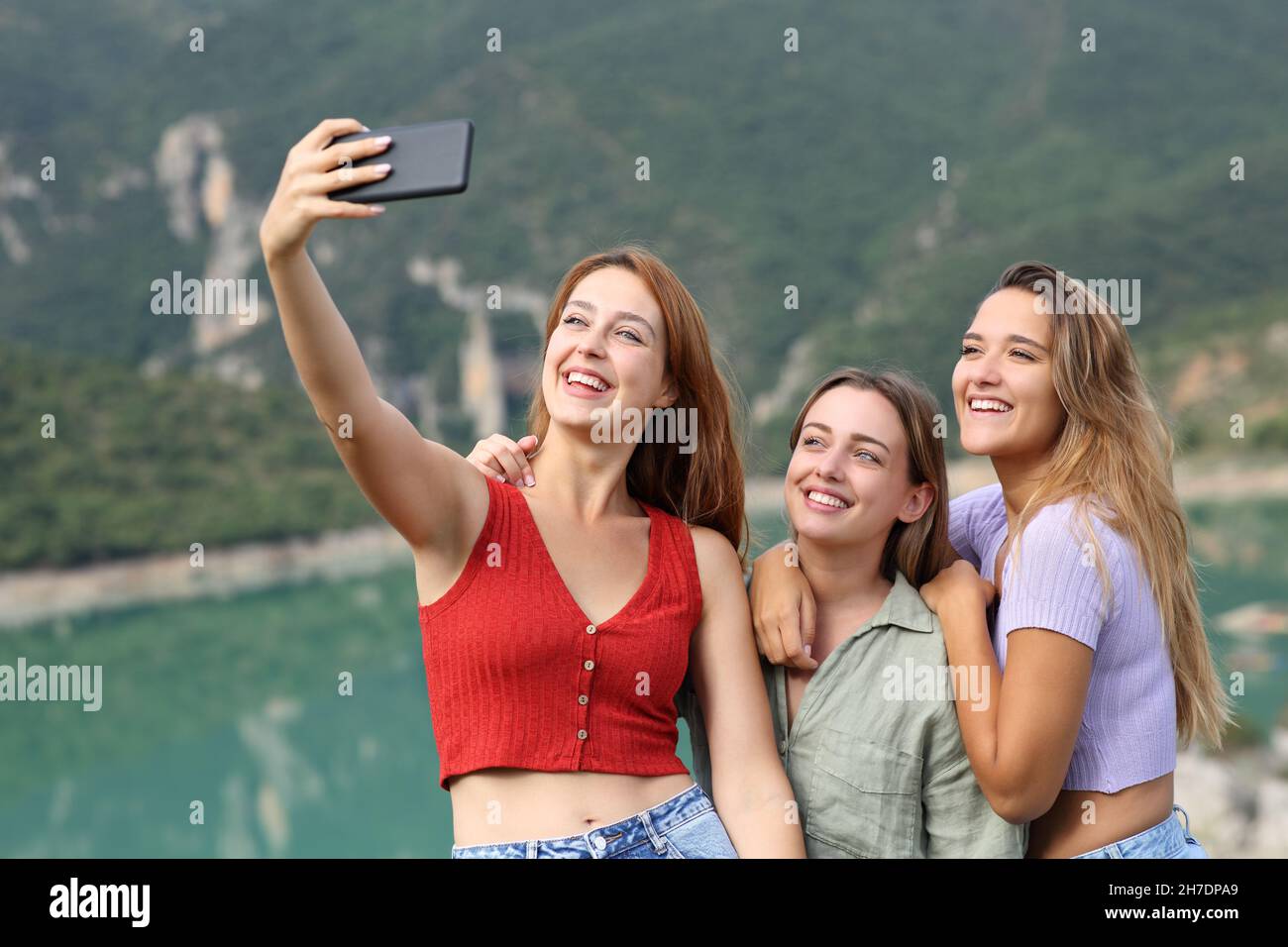 Des amis heureux prenant le selfie avec un smartphone pendant les vacances d'été dans un lac Banque D'Images