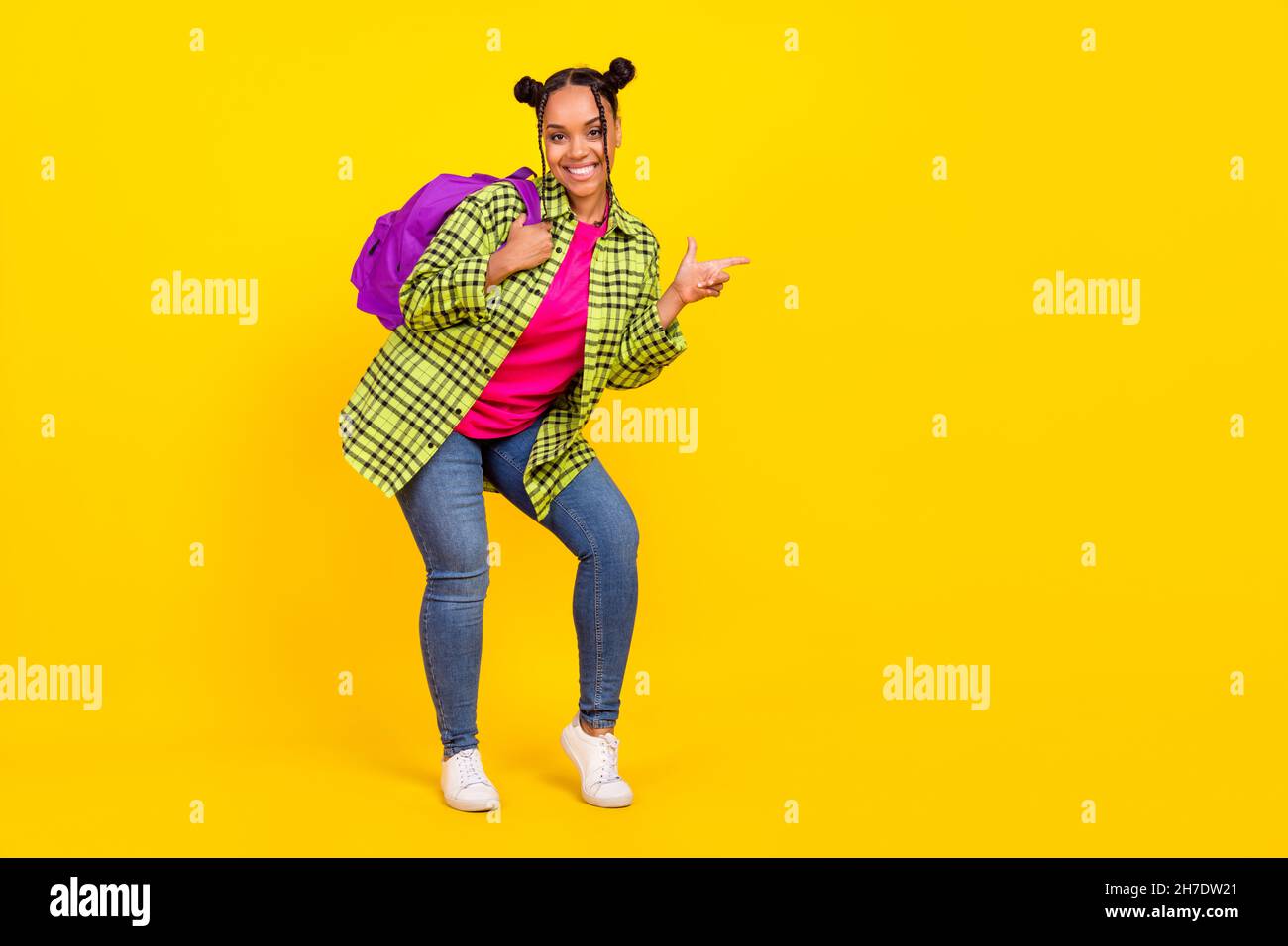 Pleine photo de joyeuse positive afro femme américaine porte sac point doigt vide espace isolé sur fond jaune Banque D'Images