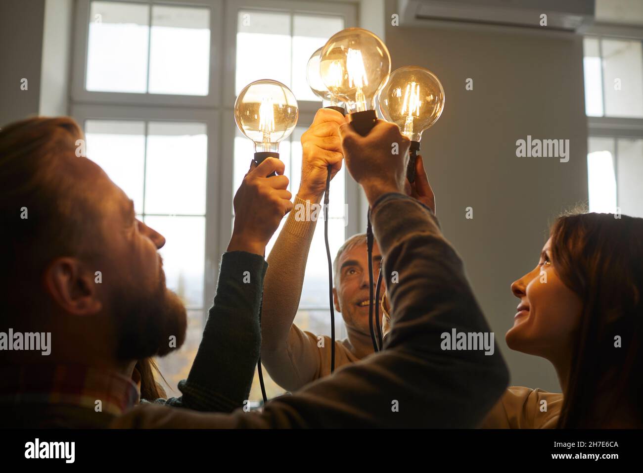 Équipe de gens heureux tenant des ampoules comme symbole d'idées créatives et d'innovations Banque D'Images