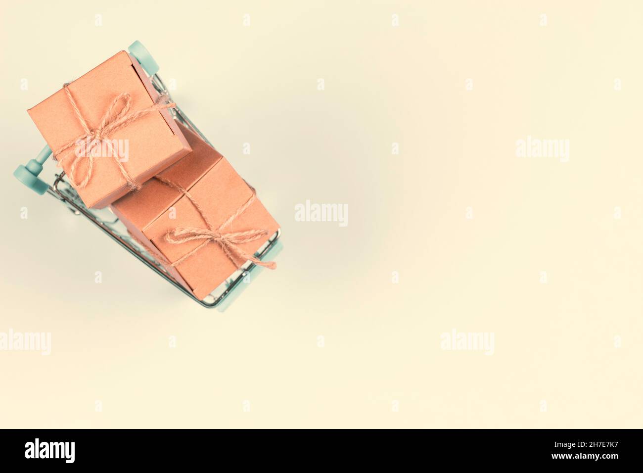 Vue de dessus à mini panier avec petit papier kraft présente boîtes-cadeaux sur fond pastel.E-commerce, concept d'achat en ligne Banque D'Images