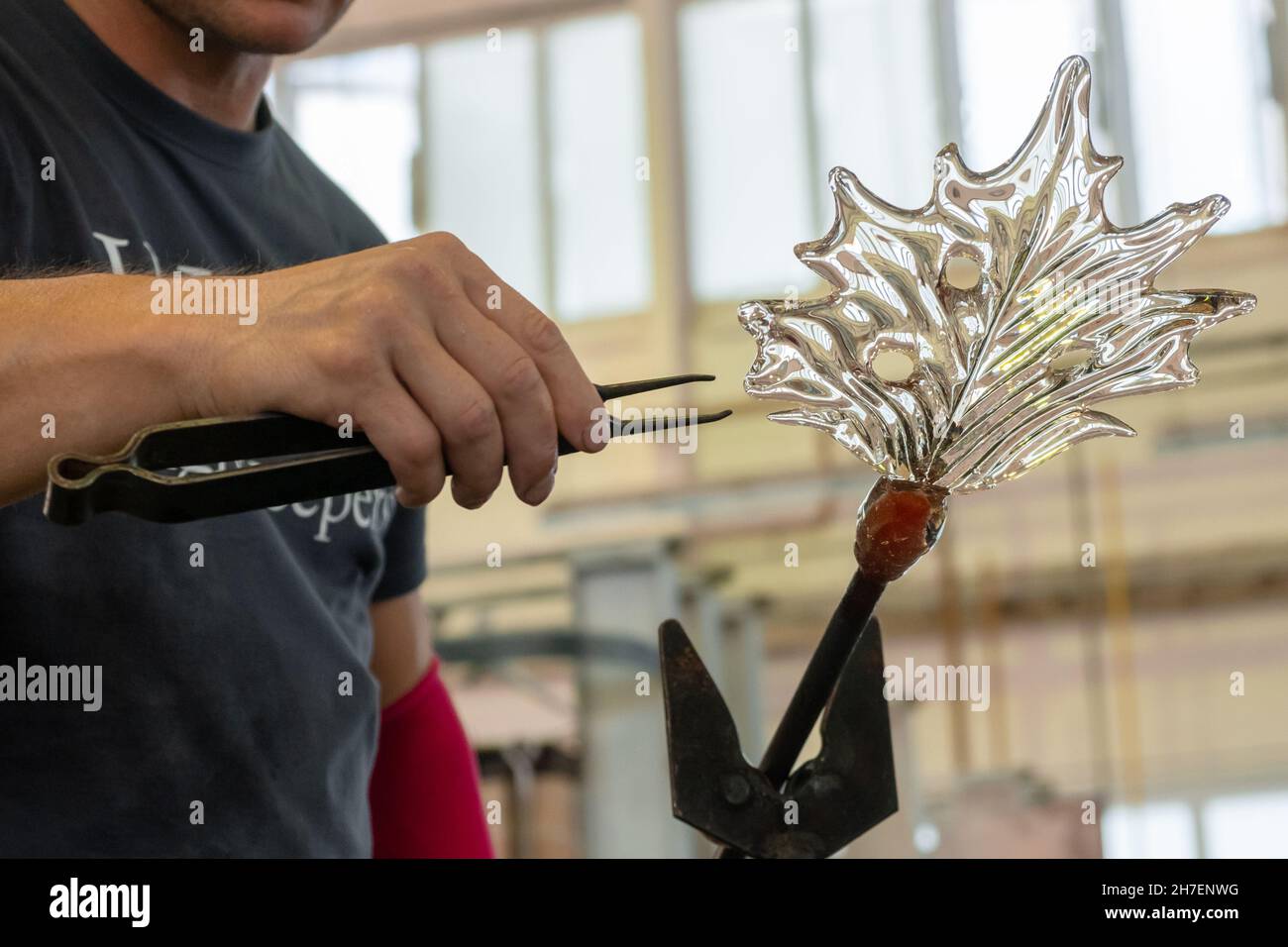 Gros plan homme fait une feuille du verre pour vase ou lustre à l'aide de pinces et de blowpipe. Banque D'Images