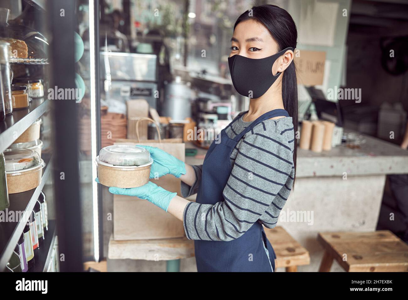Un employé de café asiatique prépare un repas à emporter pendant la fermeture du coronavirus Banque D'Images