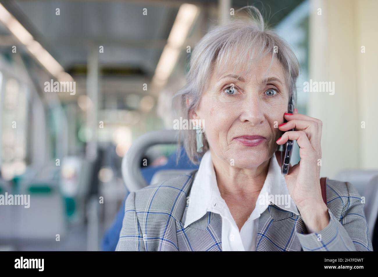 Portrait d'une femme âgée parlant au téléphone en tram Banque D'Images