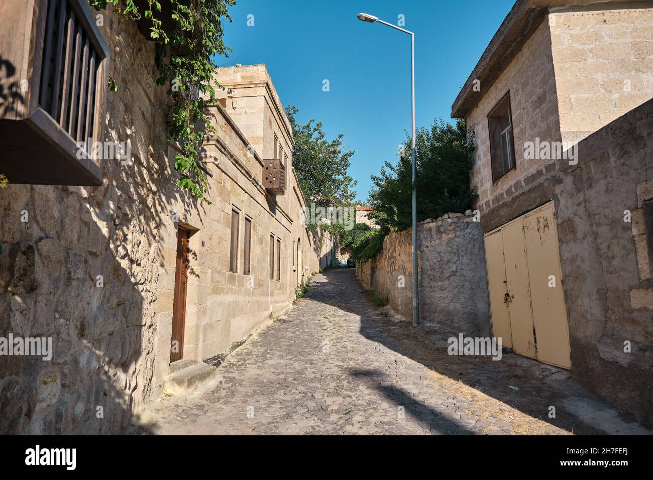 Rue étroite d'Urgup maisons traditionnelles en calcaire et rue pavée et arbres Banque D'Images