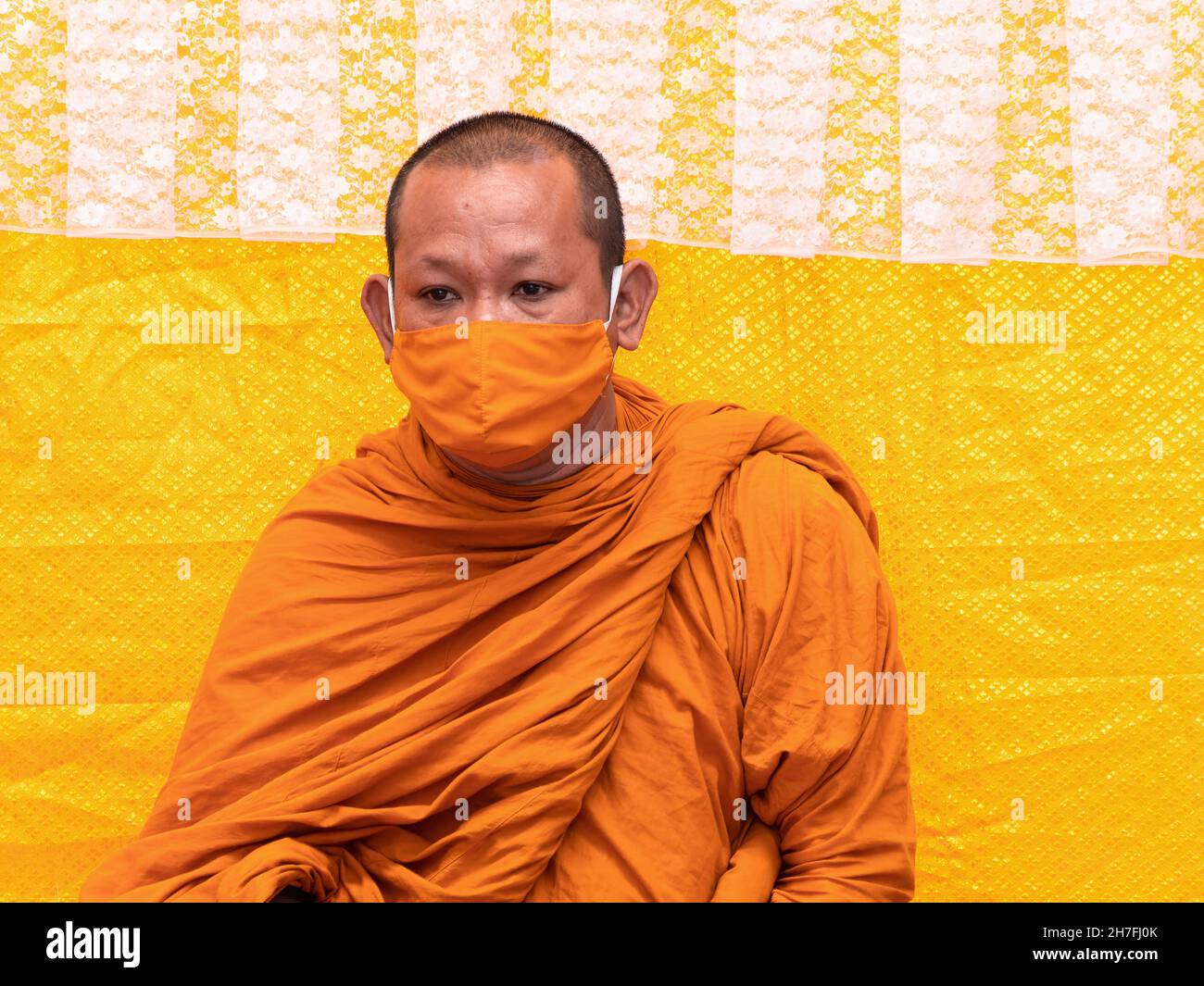 Moine bouddhiste thaïlandais avec robe orange et masque facial assorti pour protéger contre Covid-19. Banque D'Images