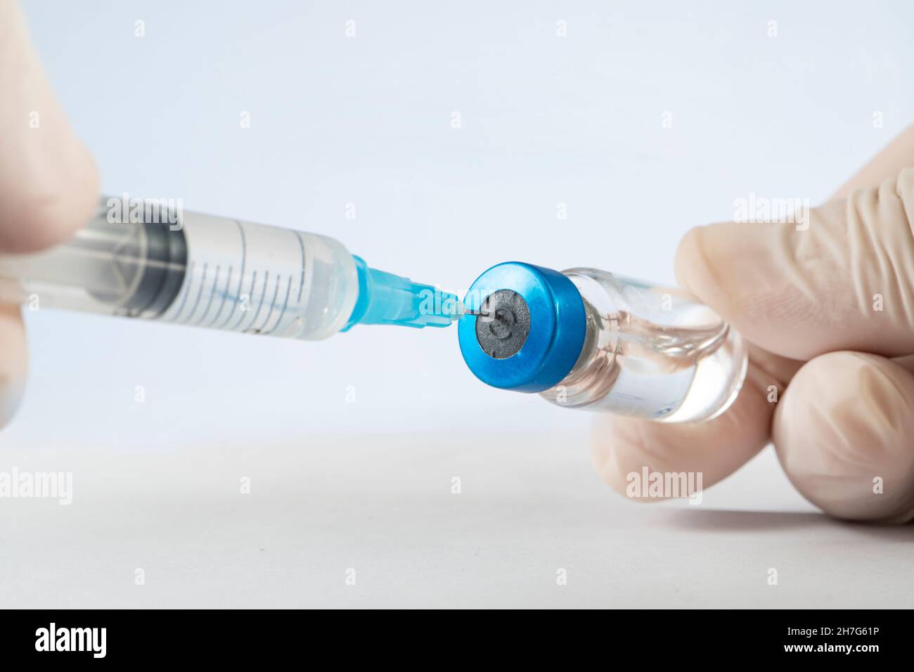 Gros plan d'un scientifique qui interagit avec une seringue percée et un flacon en verre de vaccin liquide en laboratoire. Banque D'Images