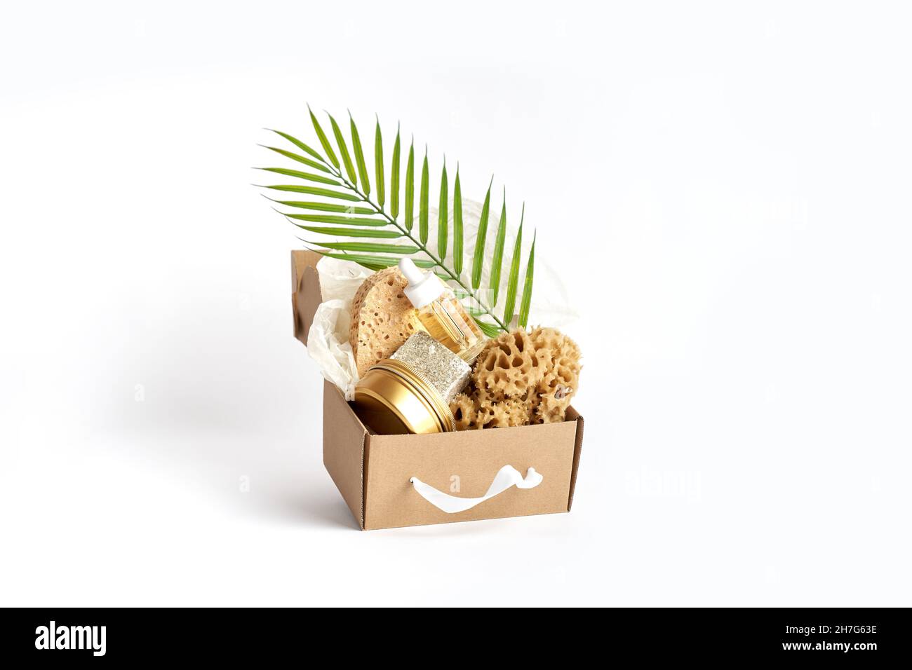 Éponges de mer naturelles, soupe, bouteille cosmétique avec huile dans une boîte artisanale sur blanc Banque D'Images