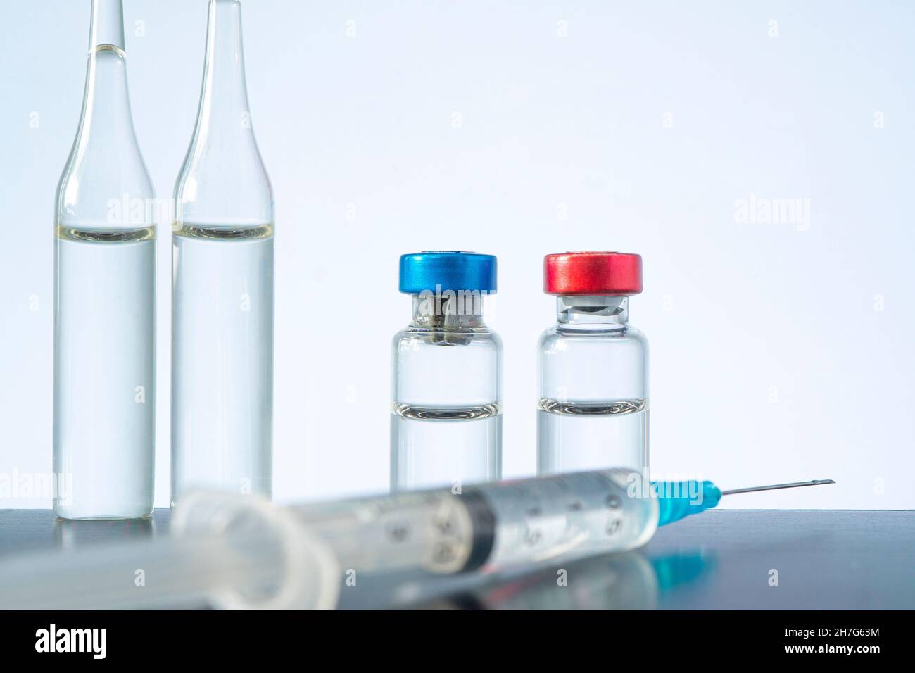 Groupe d'ampoules avec médicament et seringue sur le tableau sur fond bleu. Copier l'espace. Banque D'Images