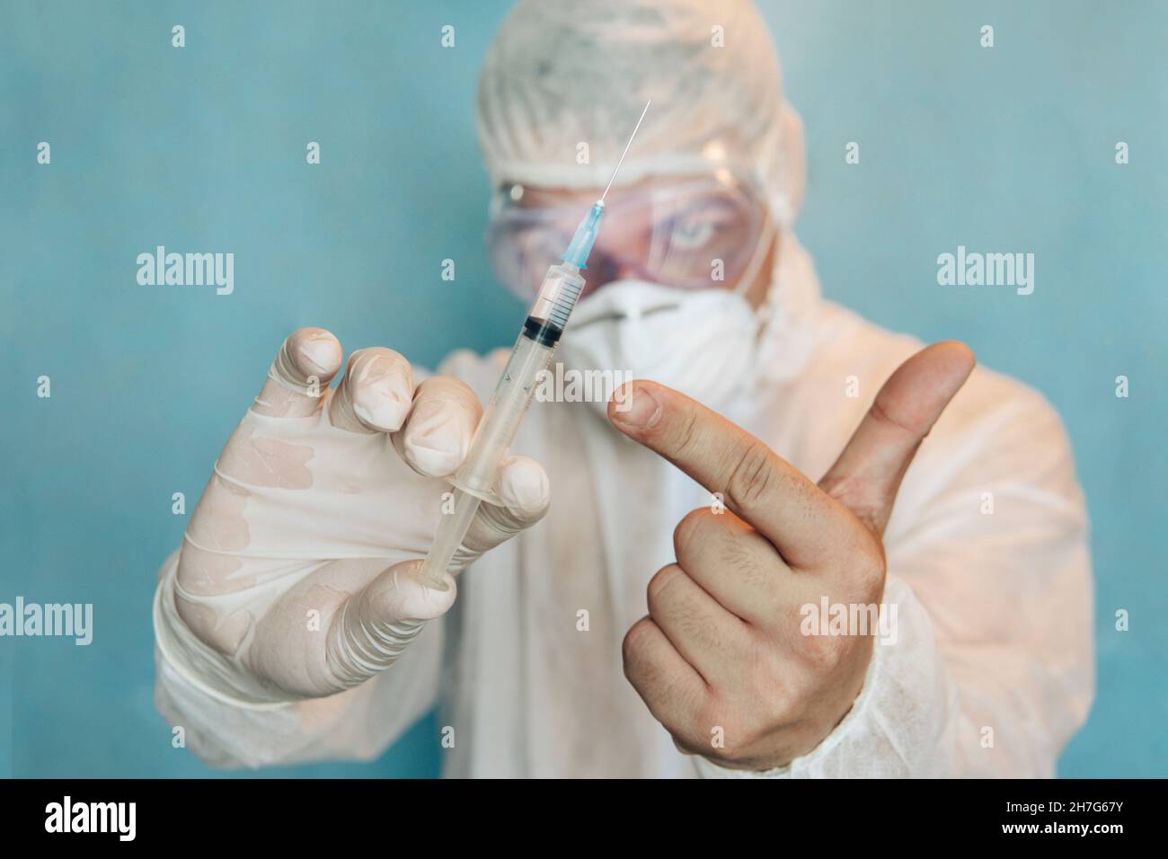 un médecin en costume protecteur tient une seringue contenant le vaccin contre le coronavirus covid 19 Banque D'Images