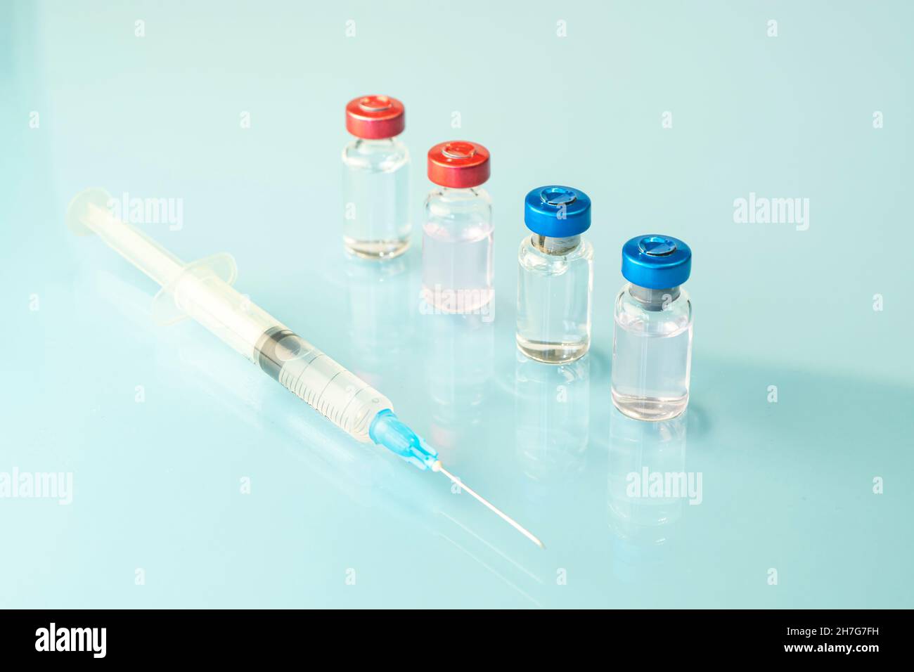 Un flacon en verre de liquide, un vaccin et une seringue médicale se rapprochent sur fond bleu.Le concept de vaccination contre le coronavirus.Bannière, copie Banque D'Images