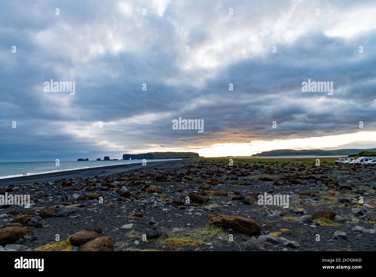 Vue panoramique sur la plage de sable noir volcanique de Reynisfjara en Islande avec quelques formations rocheuses restantes dans l'océan et des nuages sombres dans le ciel duin Banque D'Images
