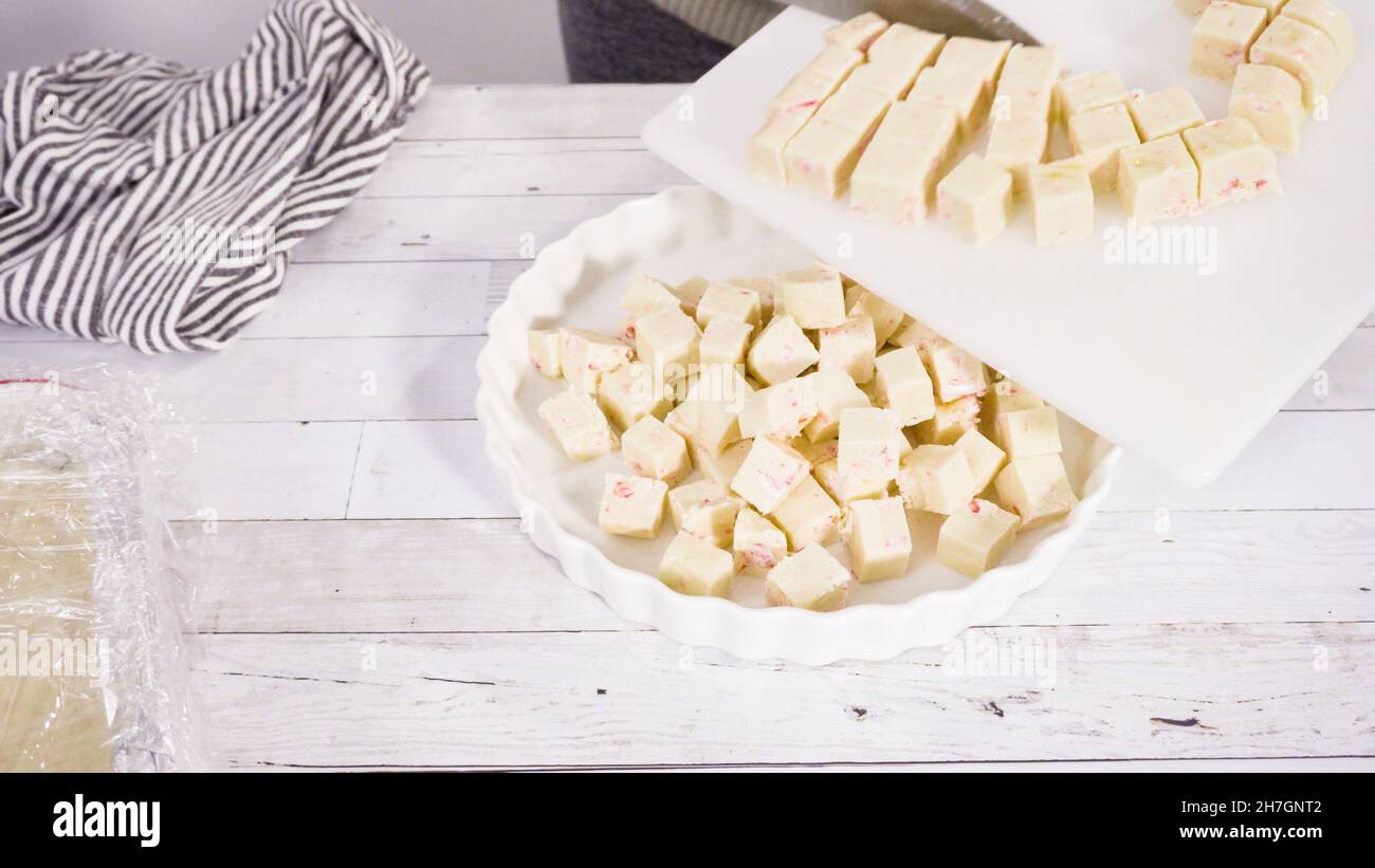 Étape par étape. Coupe de fudge de canne à sucre fait maison sur un tableau de découpe blanc. Banque D'Images