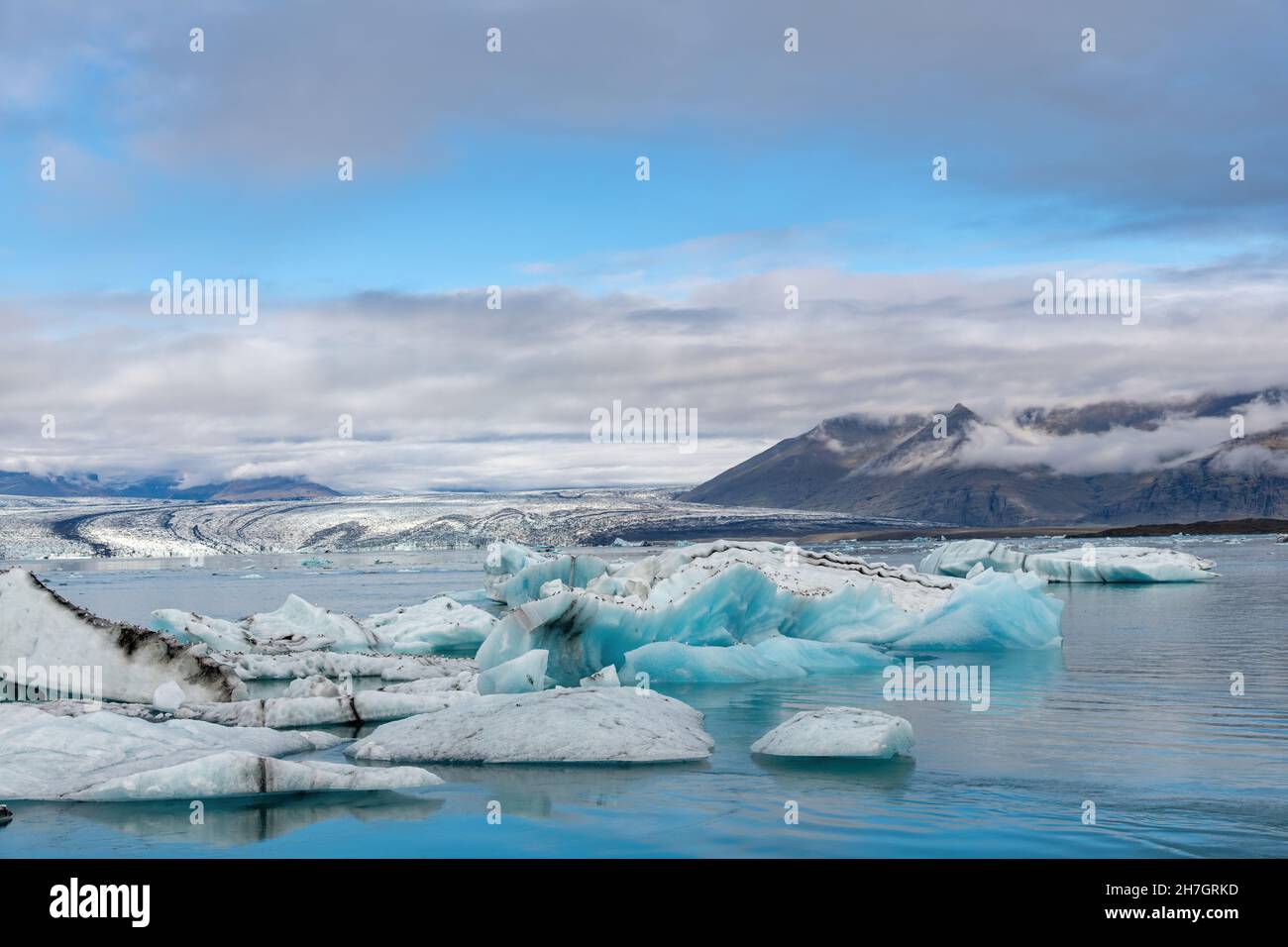 Vue panoramique sur le lagon glaciaire avec le terminus ou la fin du glacier de Jokulsarlon, Islande avec en avant-plan divers icebergs bleus de l'arctique Banque D'Images