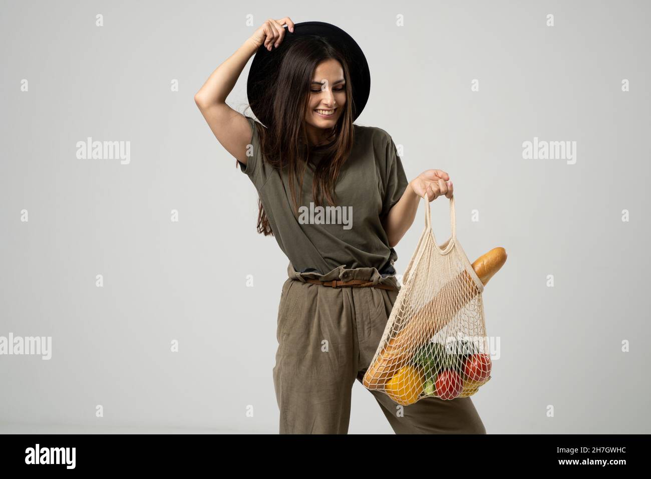 Une femme moderne et élégante avec un sac de shopping en filet avec des légumes sur le fond du studio.Le concept de nutrition saine, végétarisme Banque D'Images