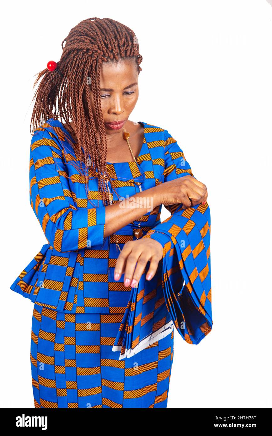 belle femme d'affaires africaine en robe traditionnelle debout sur fond blanc en ajustant son tissu de longe Banque D'Images