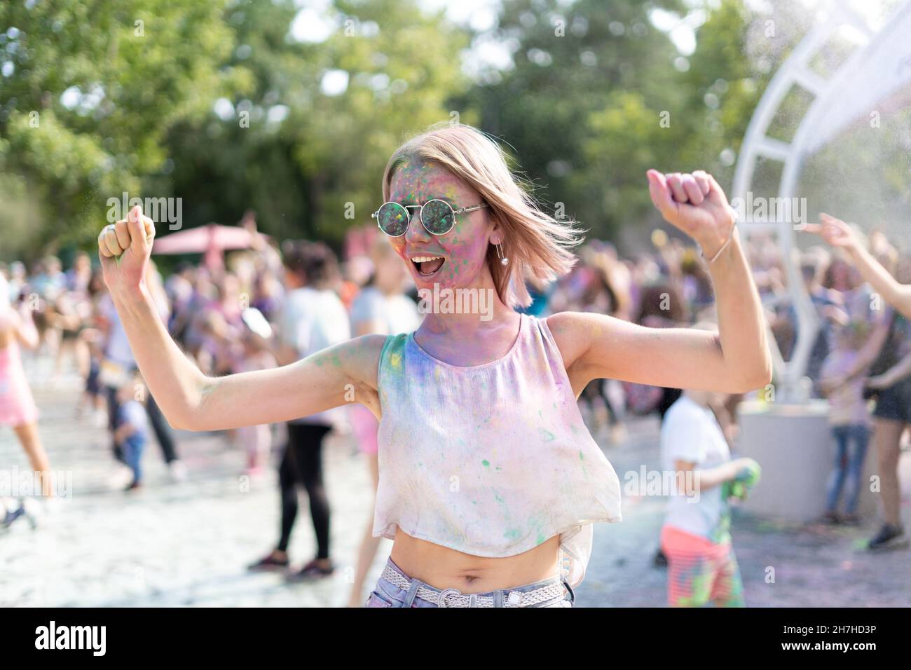 Fou de caucasienne fille au festival Holi Fest dans le parc de la ville en  été.Un festival de peintures sèches et une blonde dansant à la  musique.Concept fête d'anniversaire Photo Stock -