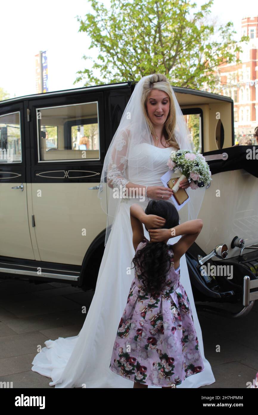 Une superbe image multi-culturelle montrant une mariée blanche de race blanche et sa personne noire de couleur fleur fille le jour de son mariage. Banque D'Images