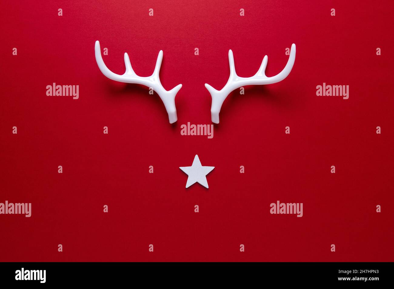 Le visage de renne de Noël est fait d'étoiles blanches et de bois blancs sur fond rouge.Concept de Noël ou de nouvel an minimal. Banque D'Images