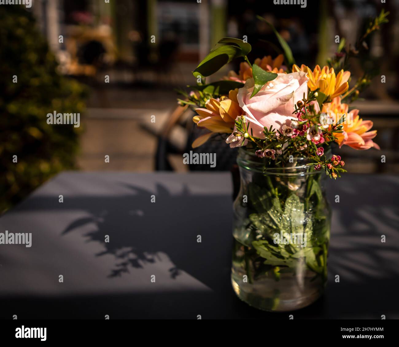 Un vase en verre avec des fleurs colorées sur la table du restaurant.Jour ensoleillé, personne.Arrière-plan avec espace de copie. Banque D'Images