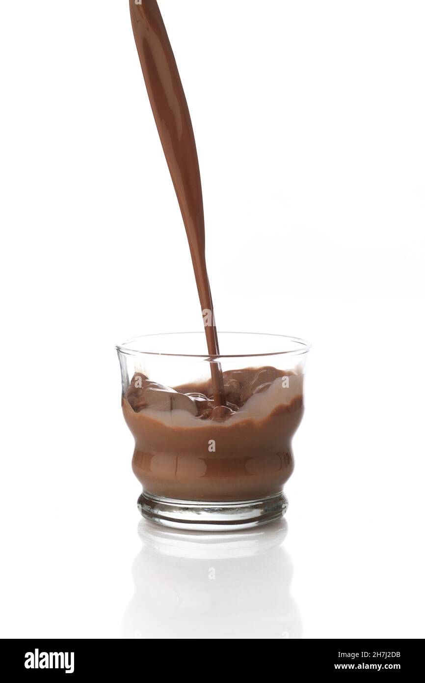 Verser la boisson au chocolat dans un verre transparent isolé dans un fond blanc avec réflexion Banque D'Images