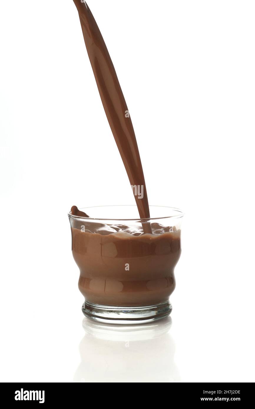 Verser la boisson au chocolat dans un verre transparent isolé dans un fond blanc avec réflexion Banque D'Images