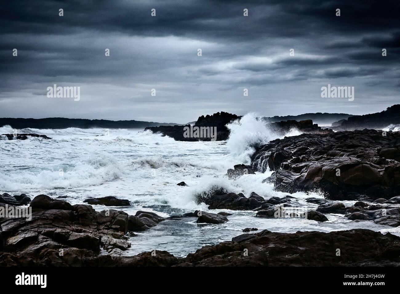 Vagues se brisant sur des rochers lors d'une sombre journée de tempête en automne au parc national de Tomaree, Nelson Bay, Nouvelle-Galles du Sud, Australie Banque D'Images