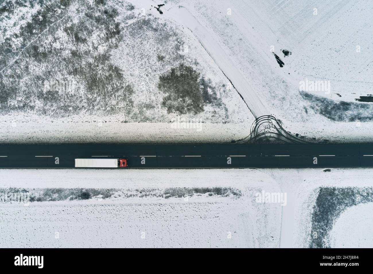Vue aérienne d'un semi-remorque roulant sur la route en hiver à travers la campagne, vue de dessus drone pov Banque D'Images