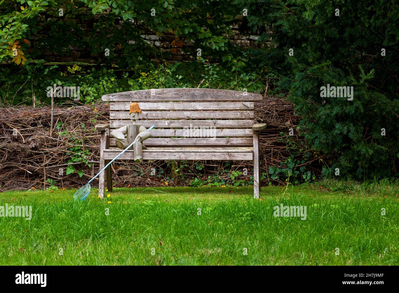 Décoration de jardin d'homme de pot de fleur assise sur un banc en bois Banque D'Images
