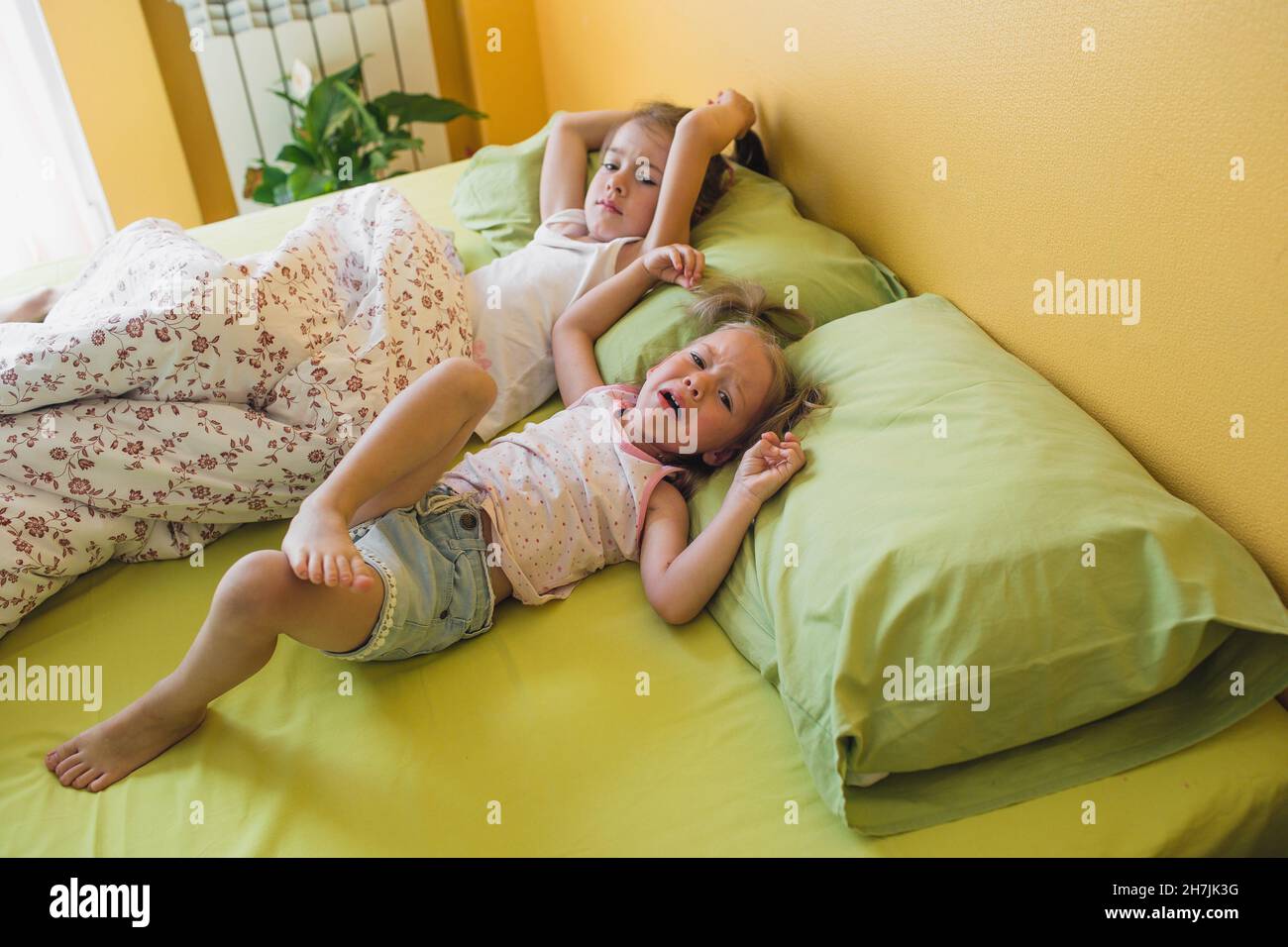 une petite fille a éclaté dans les larmes dans le lit en jouant avec sa sœur Banque D'Images