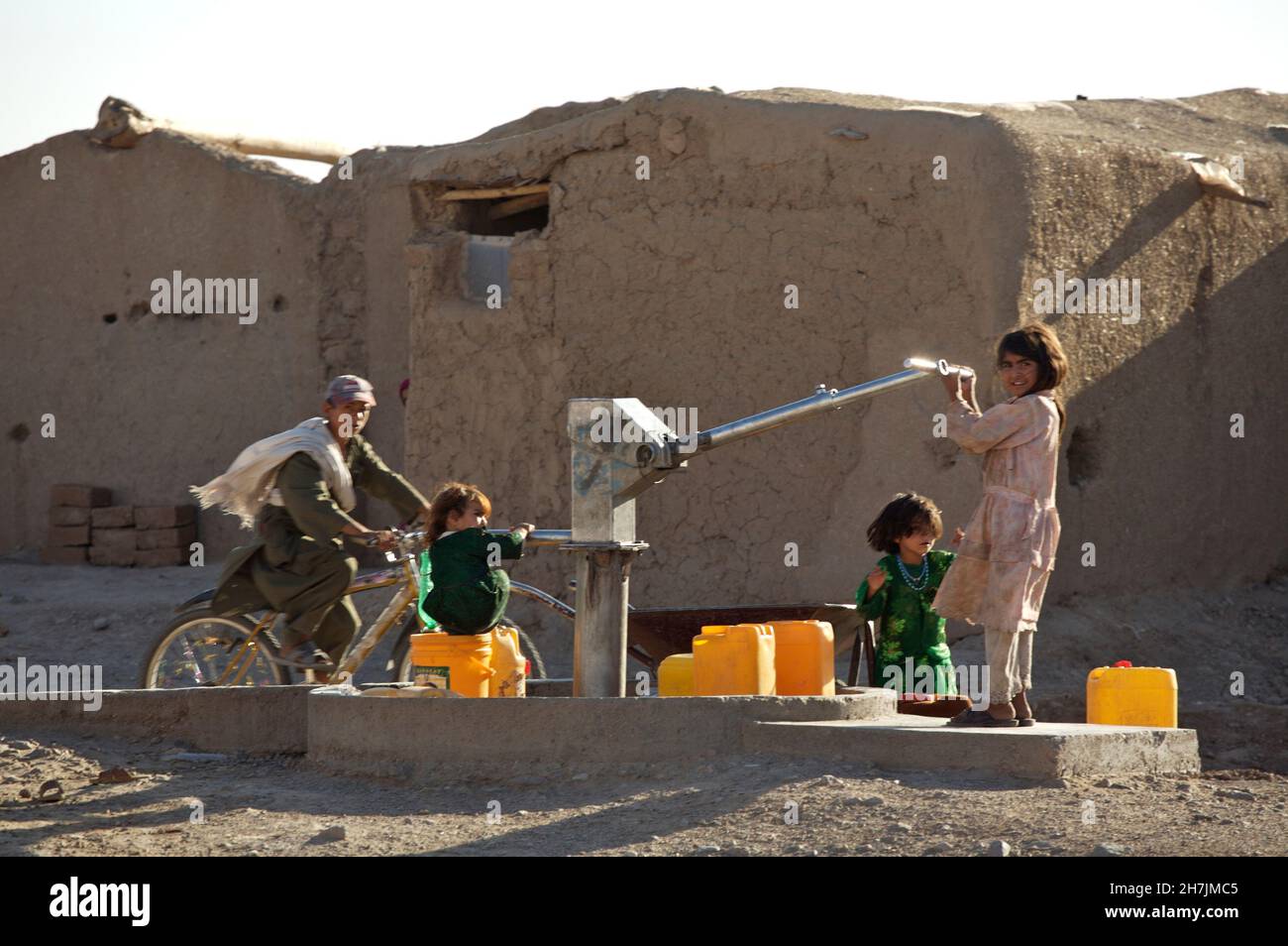 Les enfants afghans recueillent de l'eau potable à partir d'une pompe manuelle, dans le camp de Maslakh pour les personnes déplacées, à la périphérie de la ville du nord-ouest o Banque D'Images
