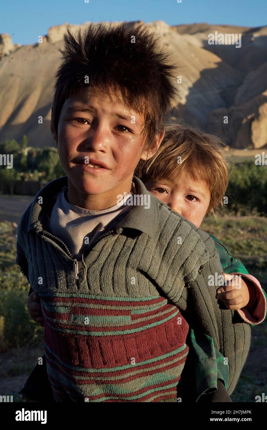 Un garçon ethnique Hazara porte sa petite sœur sur son dos dans le village de Ragshad, à la périphérie de la ville de Bamyan, dans le centre de la province de Bamyan.AF Banque D'Images