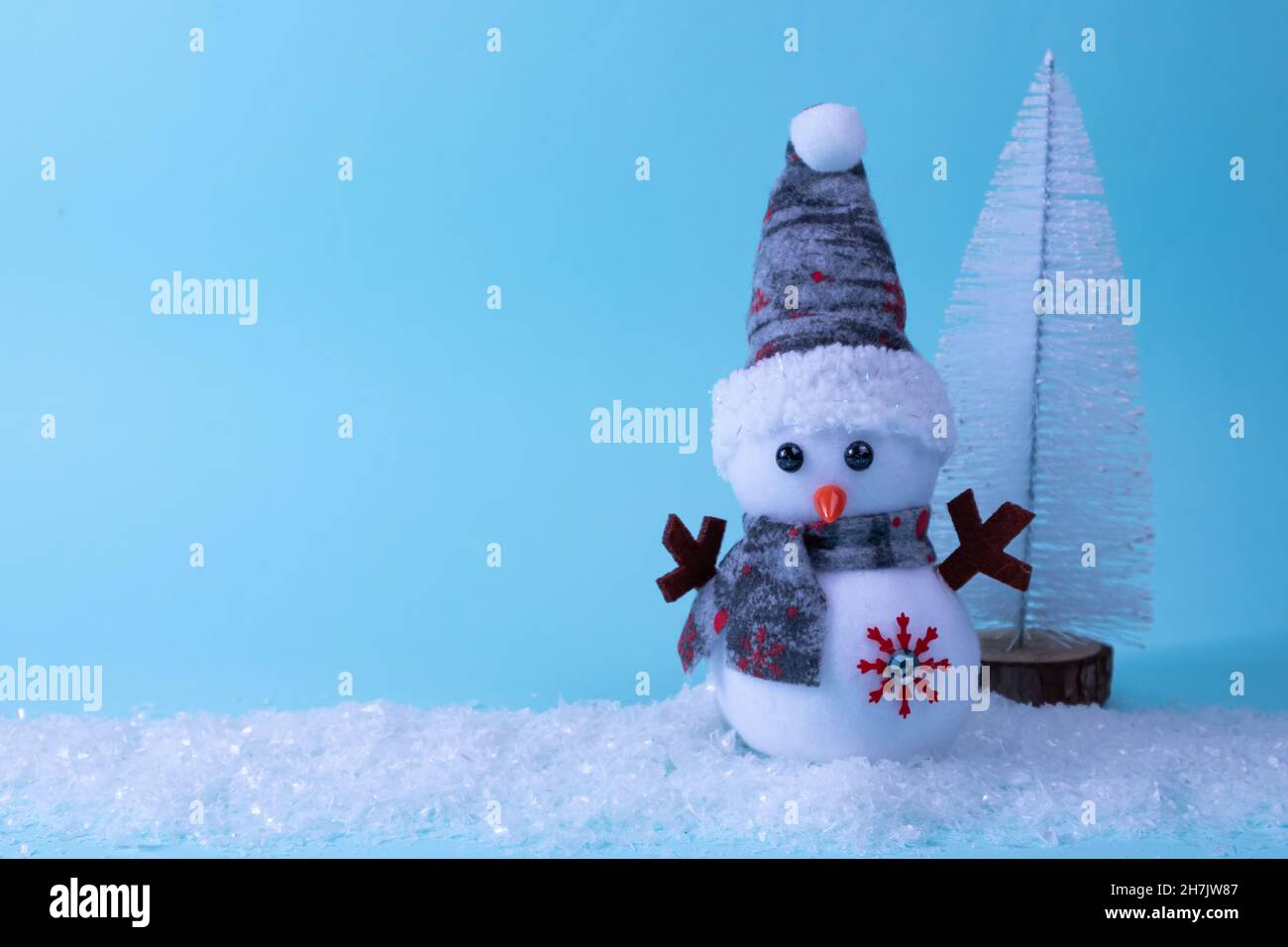 Bonhomme de neige et sapin de Noël sur neige blanche sur fond bleu.Carte de Noël pour le nouvel an.Place pour une inscription. Banque D'Images