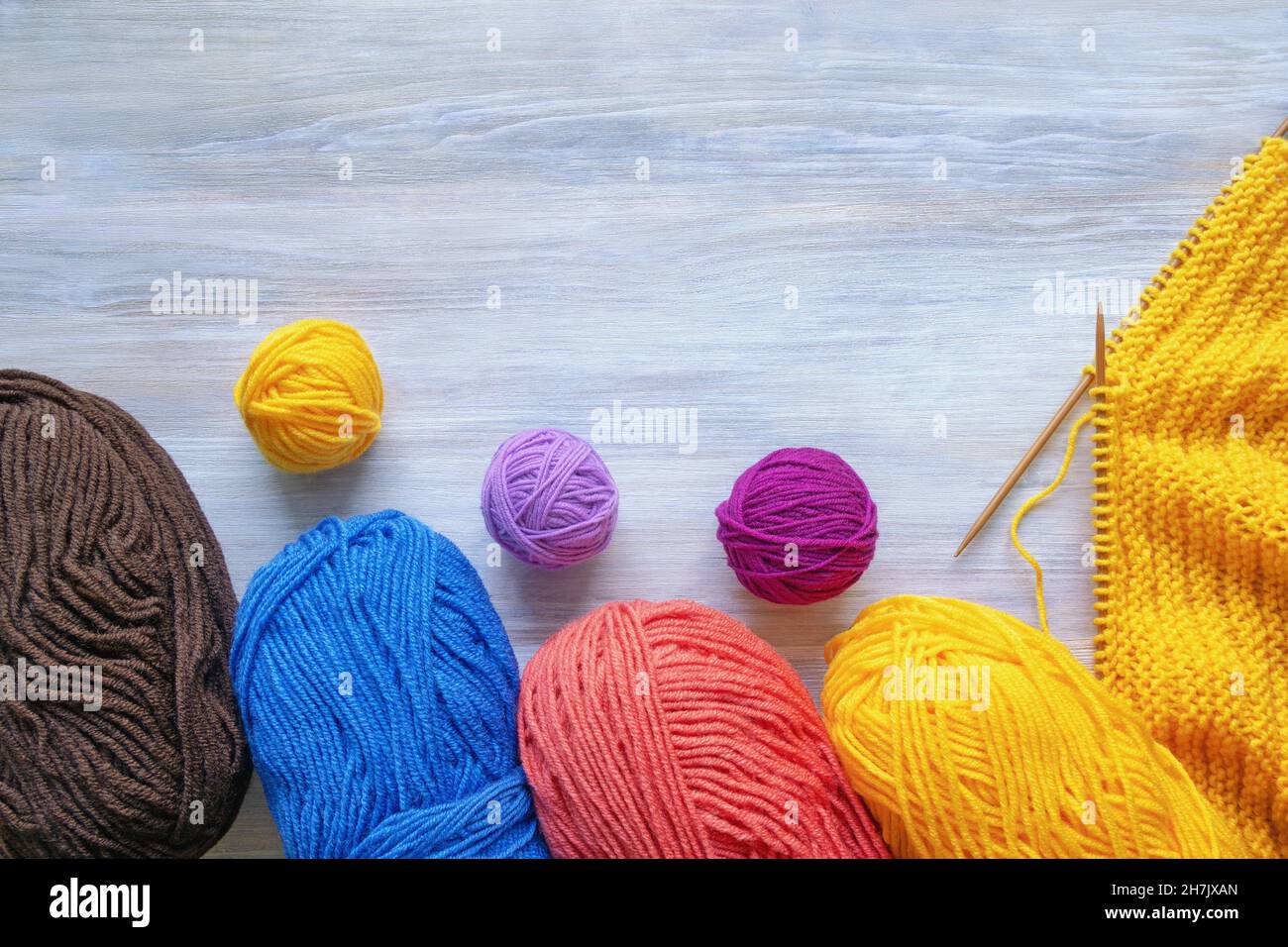 Passe-temps et concept de tricotage.Boules colorées de laine et aiguilles à tricoter sur table rustique.Espace libre pour le texte Banque D'Images