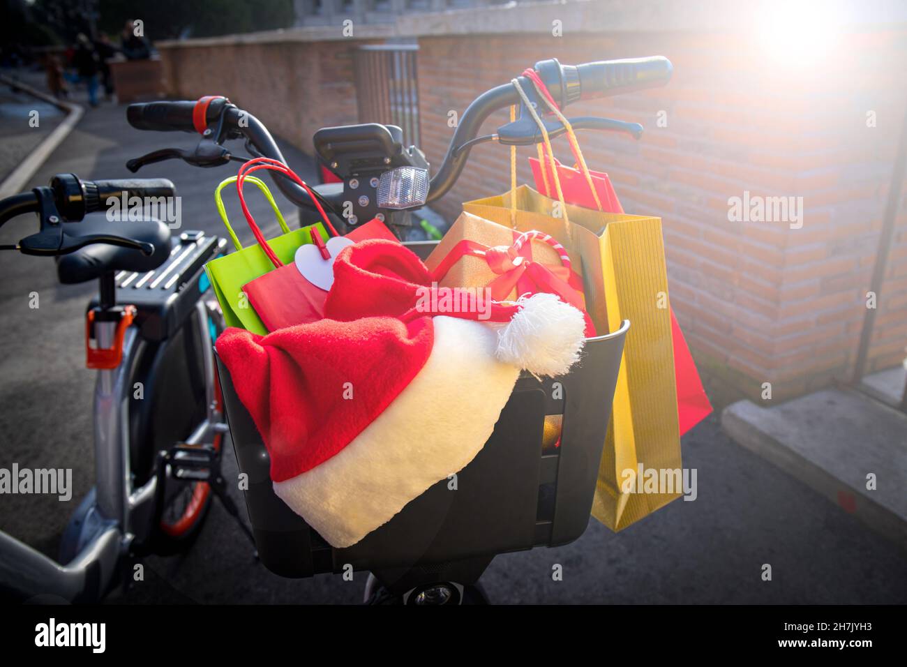 Shopping de Noël.Panier à vélo plein de cadeaux de Noël et de sacs cabas colorés.Chapeau du Père Noël reposant sur les cadeaux. Banque D'Images