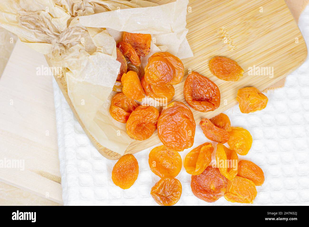 Abricots séchés à l'orange sur fond de bois clair. Banque D'Images
