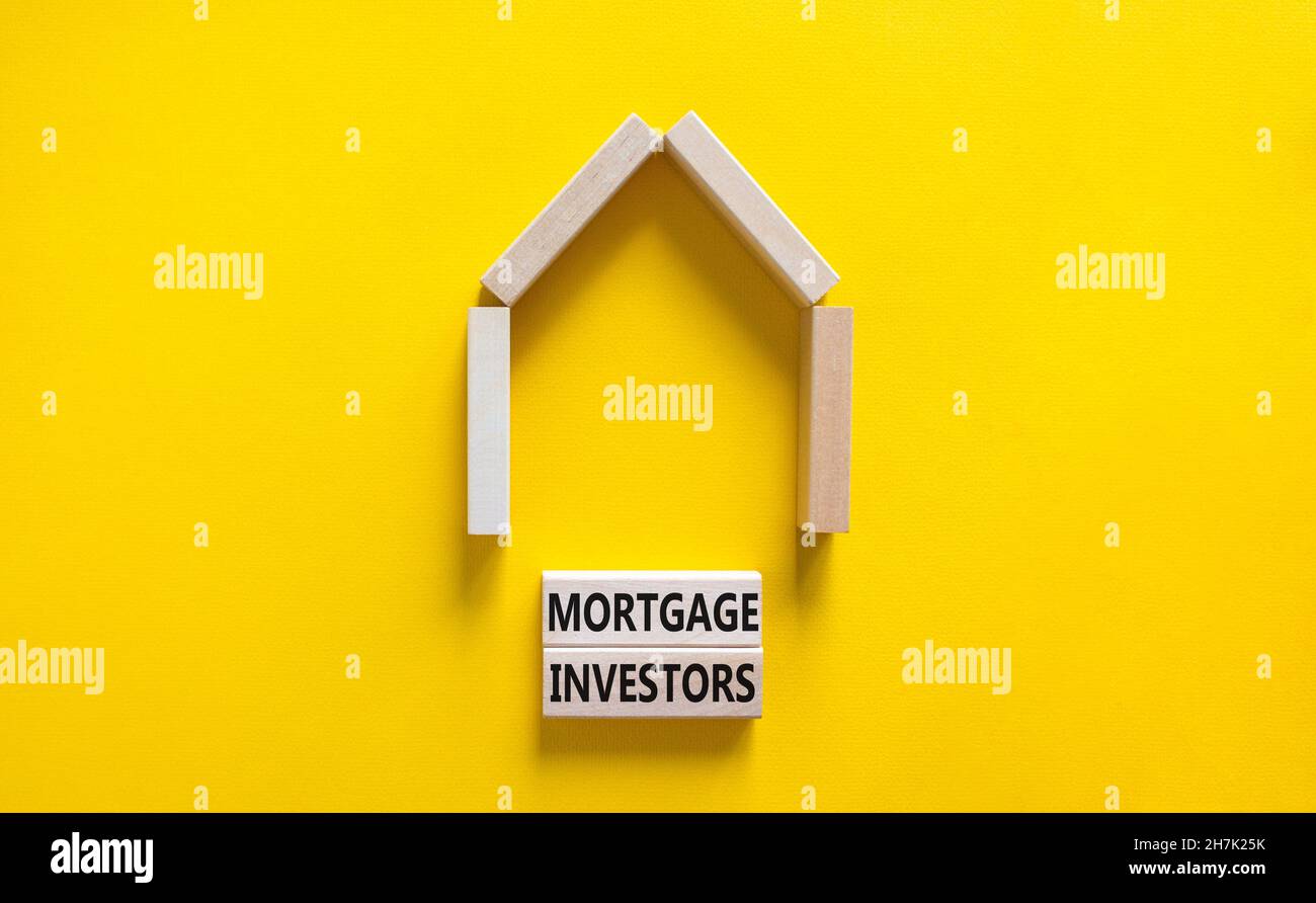 Symbole des investisseurs hypothécaires.Mots-clés 'Mortgage Investors' sur des blocs de bois près de la maison en bois miniature.Magnifique fond jaune.Affaires, plus Banque D'Images