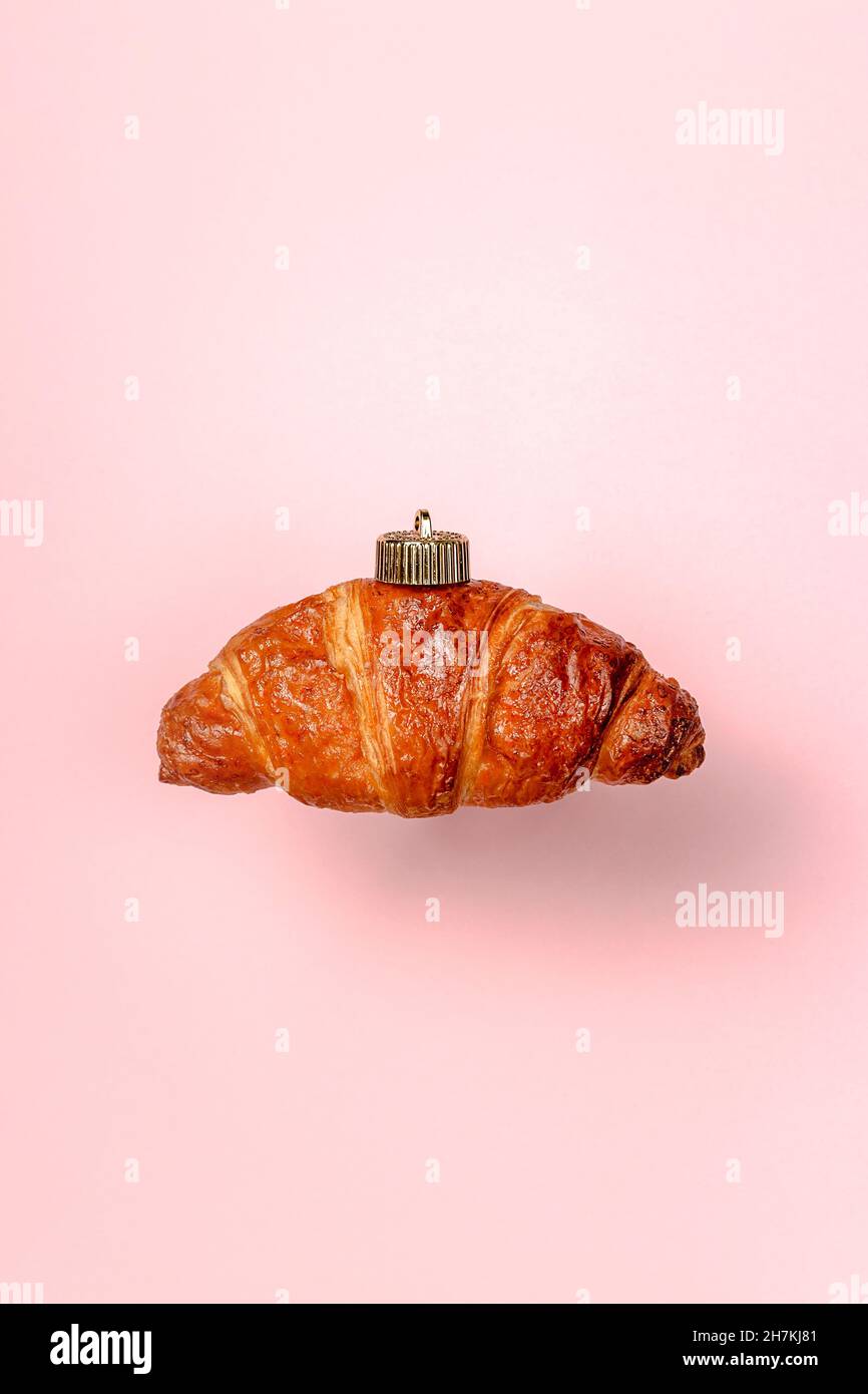 décoration de boule de noël faite de croissant sur fond rose. Concept minimal du nouvel an. Gros plan Banque D'Images