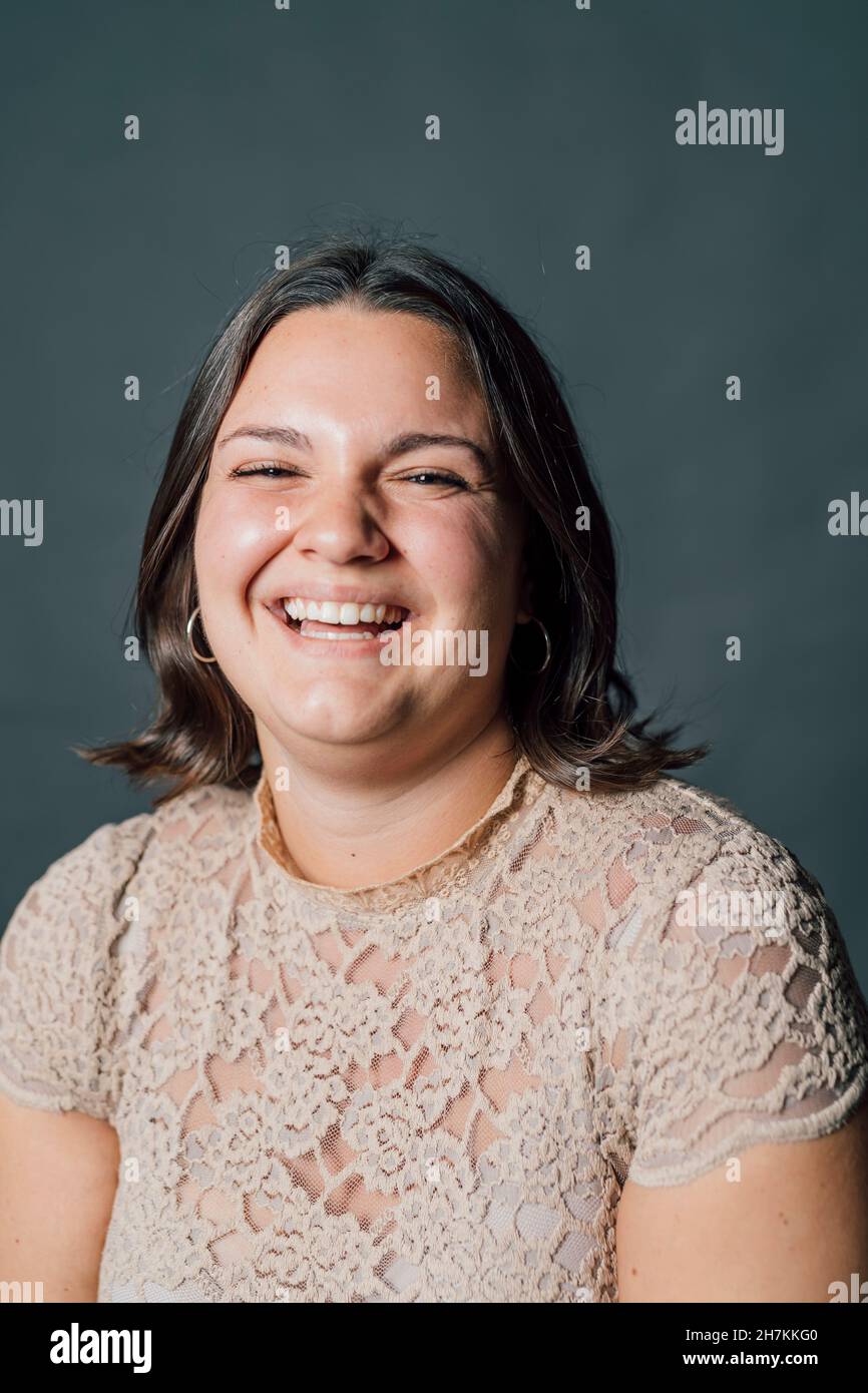 Jeune femme riant sur fond gris Banque D'Images