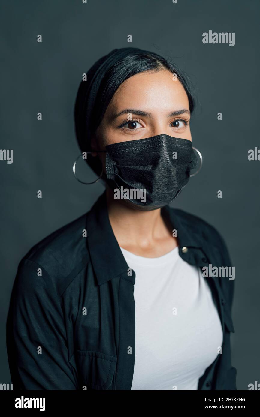 Femme portant un masque de protection noir sur fond gris Banque D'Images