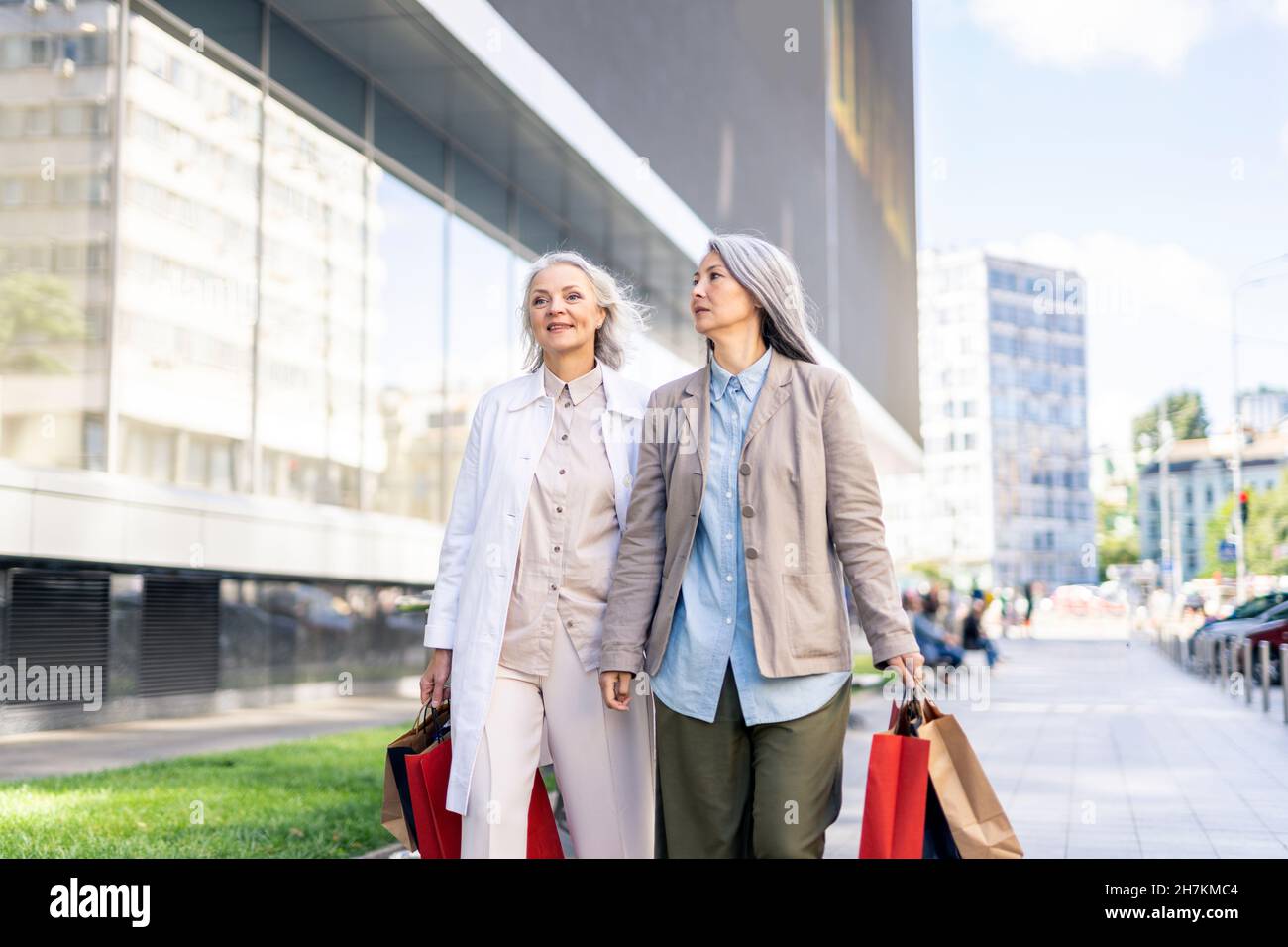 Des femmes matures avec des sacs de shopping marchant sur le sentier près du centre commercial Banque D'Images