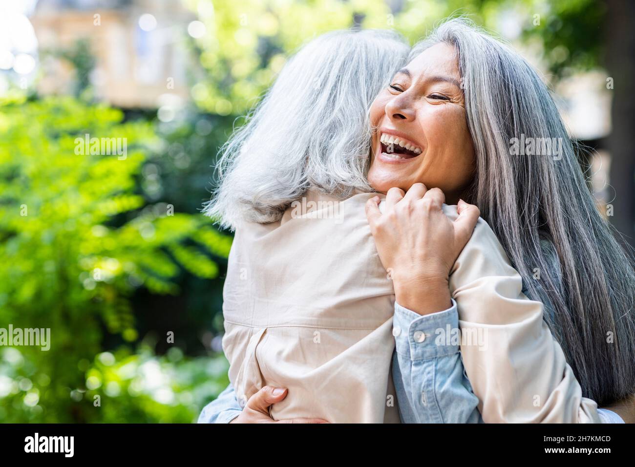 Les femmes matures rient tout en embrassant leur amie Banque D'Images