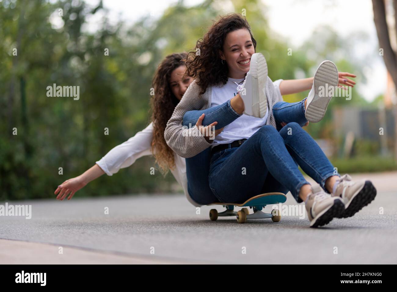 Amis féminins assis sur le mur de soutènement Banque D'Images