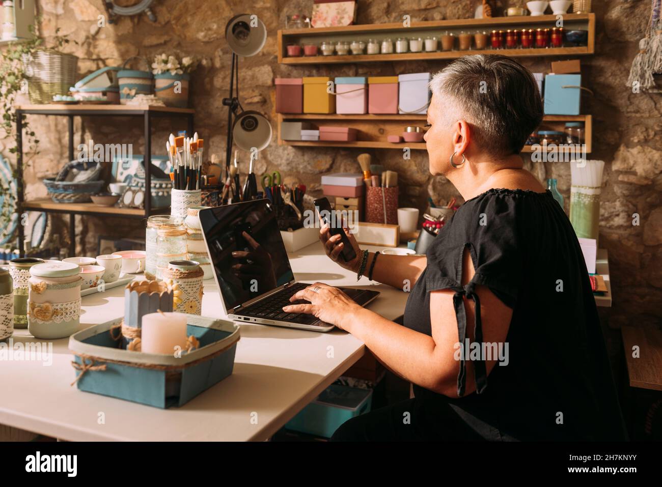 Une artiste souriante utilisant un ordinateur portable sur son lieu de travail Banque D'Images