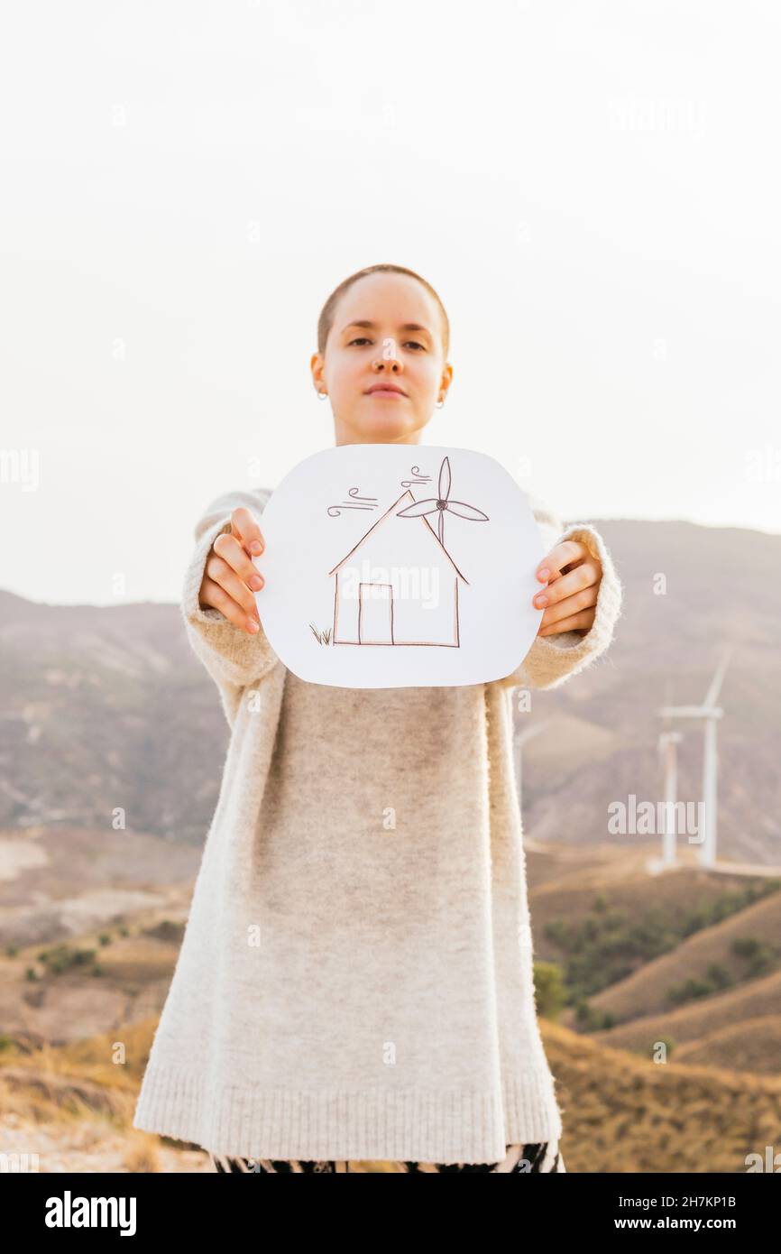 Femme tenant du papier avec dessin de maison en se tenant debout sur la montagne Banque D'Images