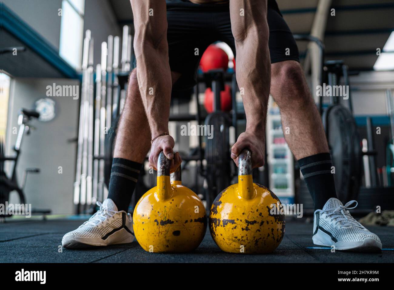Athlète musclé de sexe masculin tenant des kettlebells dans la salle de sport Banque D'Images