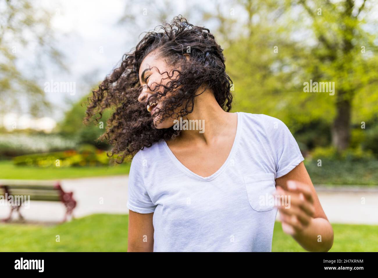 Femme insouciante se jetant les cheveux au parc Banque D'Images
