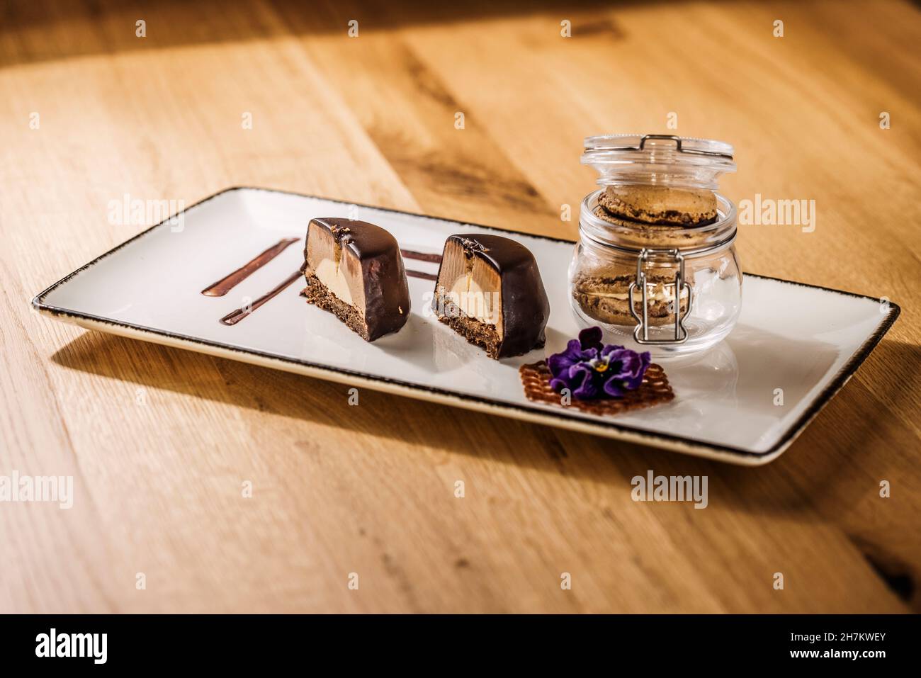 Plateau avec demi-gâteau au chocolat et pot de biscuits au macaron Banque D'Images