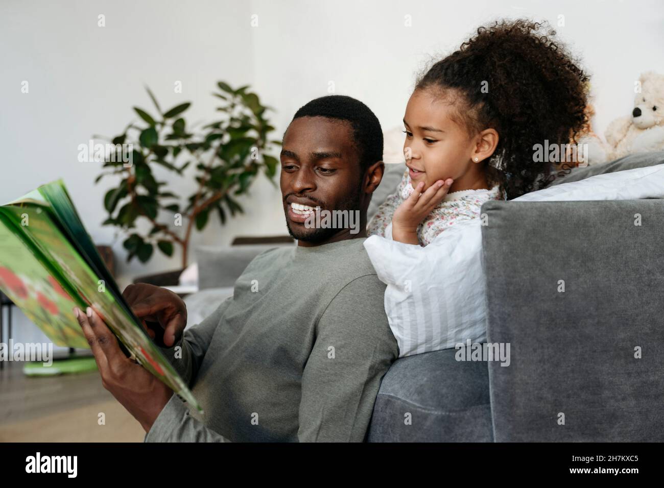 Un jeune homme racontant une histoire à sa fille dans le salon Banque D'Images